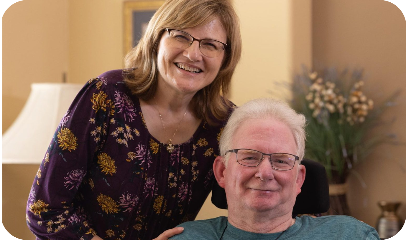 A caregiver posing with a an elderly man