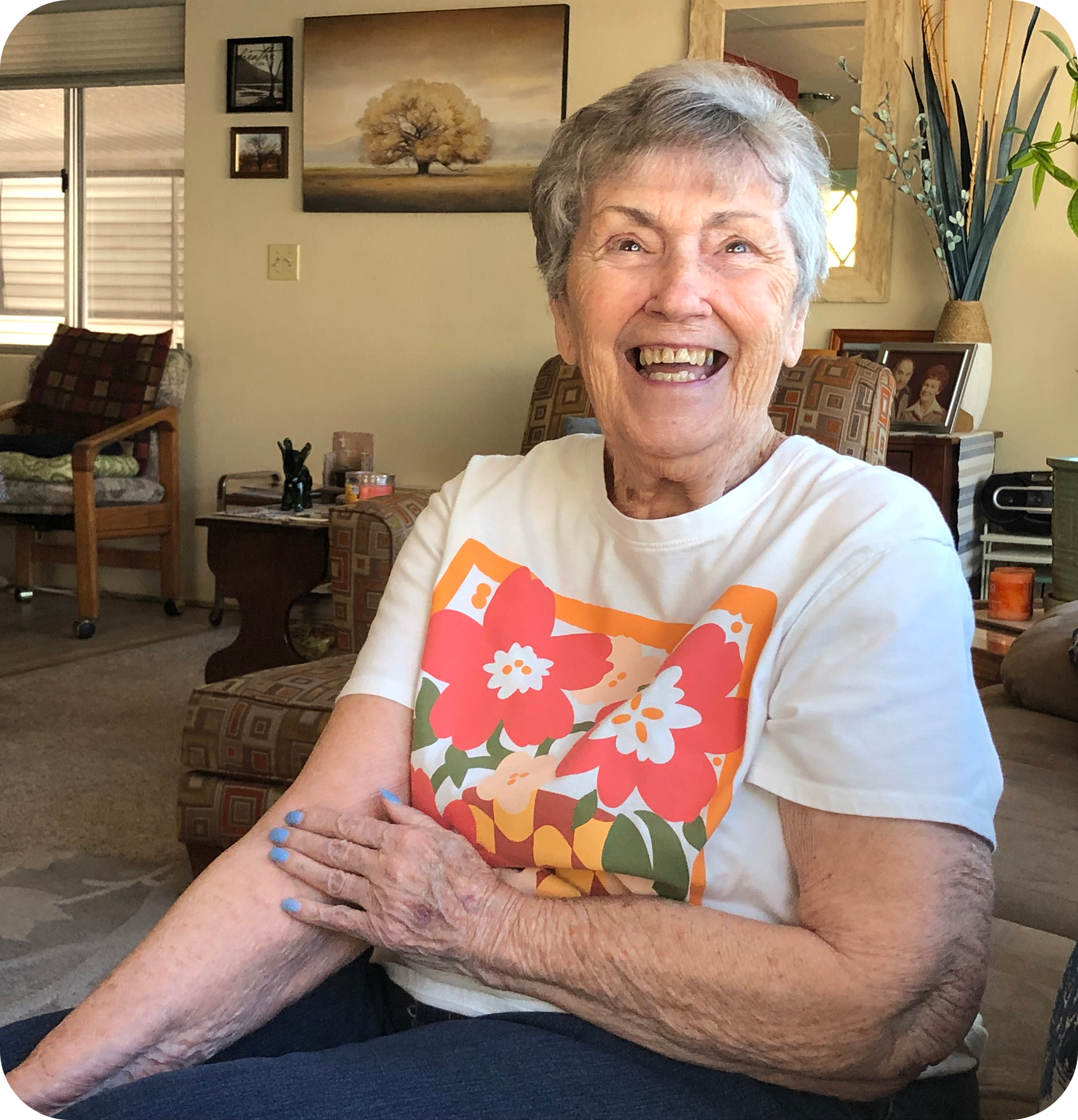 An elderly woman smiling while sitting on her couch